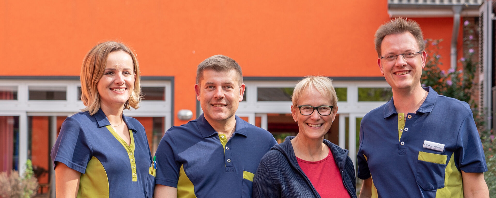 Eine Gruppe von Pfleger*innen die vor der Fassade des Christlichen Reha Hauses stehen und in die Kamera lächeln