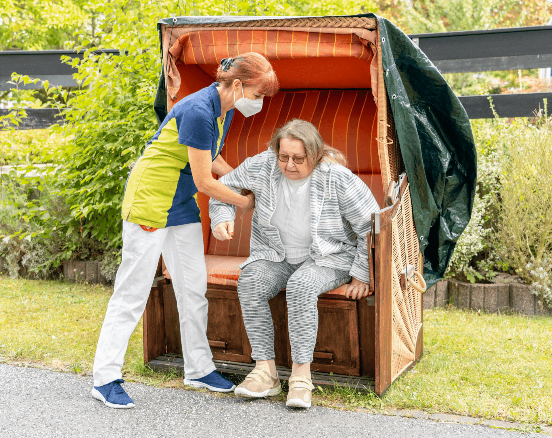 Eine Pflegerin hilft einer Bewohnerin aufzustehen.