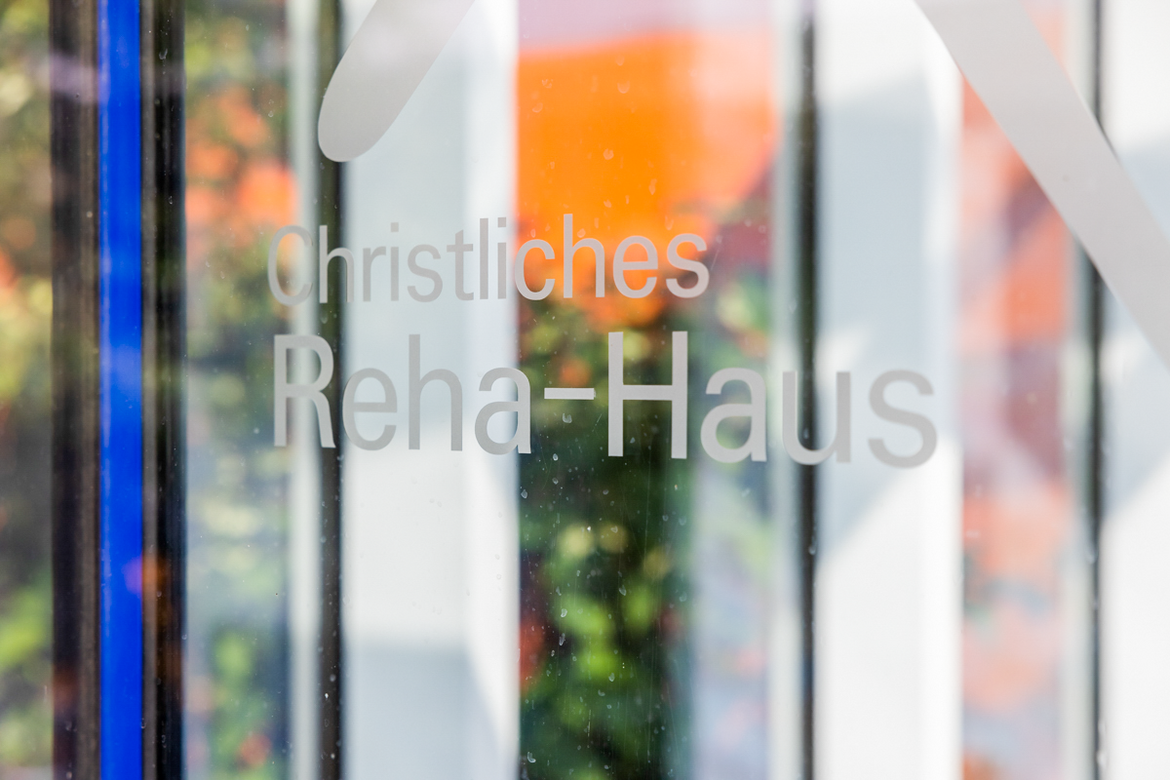 Schriftzug "Christliches Reha-Haus" auf einer Glasscheibe.