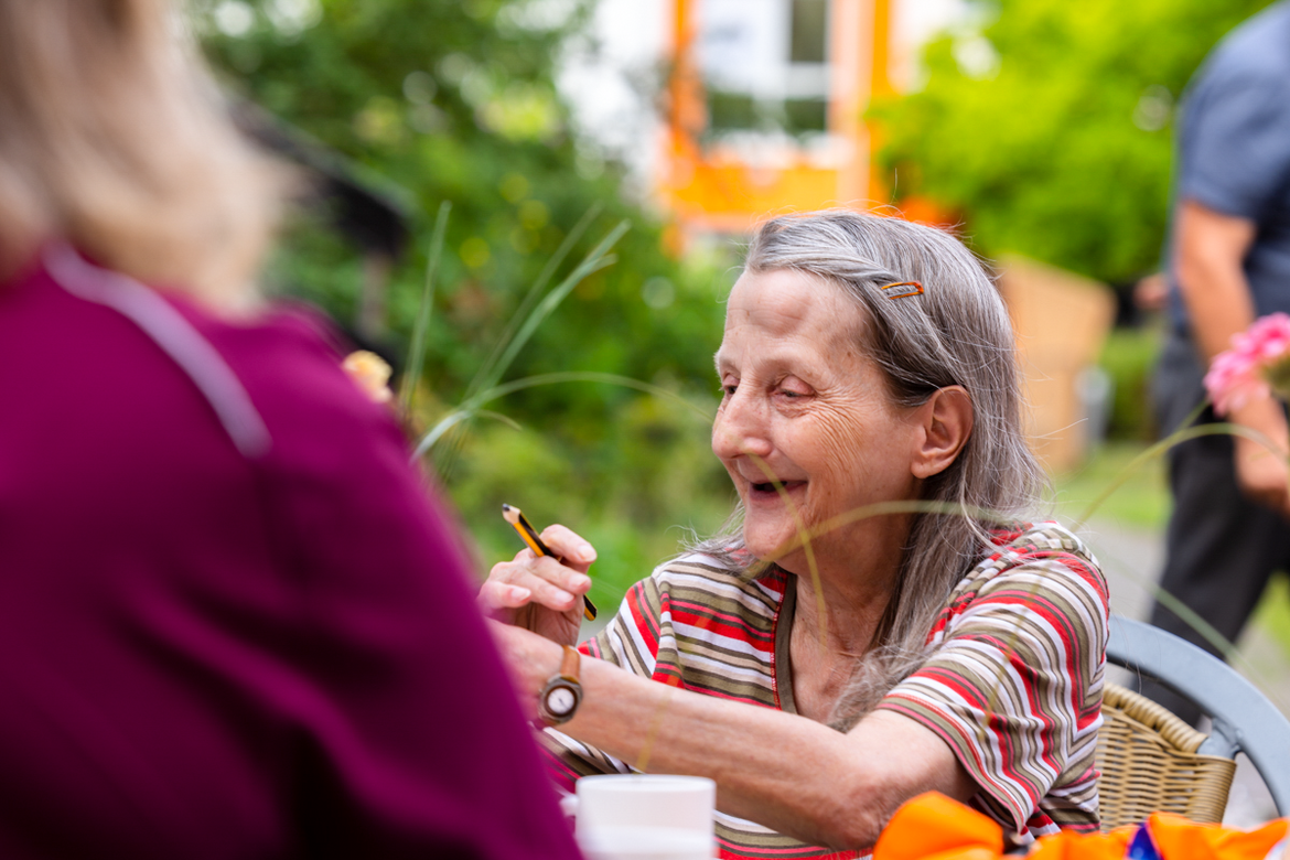 Auf der Terrasse freut sich eine Bewohnerin über ihren Bingogewinn.