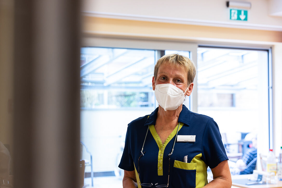 Eine Pflegerin mit Maske guckt in die Kamera. 